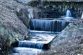 Small stream with waterfalls exiting old dam Royalty Free Stock Photo
