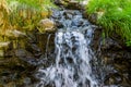 Small streaming waterfall, water flowing over rocks, beautiful nature background Royalty Free Stock Photo