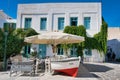 Small street cafe with empty chairs and a decorative boat under a white umbrella. Parikia, Paros.