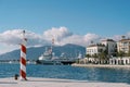 Small striped lighthouse stands on the pier of a luxury marina with moored yachts Royalty Free Stock Photo