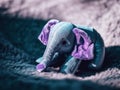 A small stuffed elephant laying on a blanket. Generative AI image.