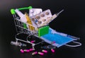 Small supermarket cart with pills, ampoules, thermometer, medical mask on a black background. Concept of protection against viral Royalty Free Stock Photo