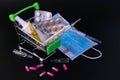 Small supermarket cart with pills, ampoules, thermometer, medical mask on a black background. Concept of protection against viral Royalty Free Stock Photo