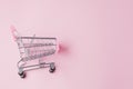 Small supermarket grocery push cart for shopping toy with wheels and pink plastic elements on pink pastel color paper flat lay Royalty Free Stock Photo