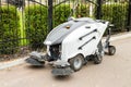 Small sweeper machine standing at parking storage after cleaning city park alley.Sweeping vacuum cleaner vehicle removing dust and Royalty Free Stock Photo