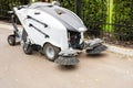 Small sweeper machine standing at parking storage after cleaning city park alley.Sweeping vacuum cleaner vehicle removing dust and Royalty Free Stock Photo