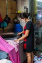 In a small tailor shop in Saigon. A woman irons fabric