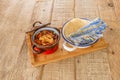 Small tart pan full of choriqueso tacos, next to an enameled metal bowl full of corn tortillas for tacos with a string napkin to