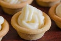 Small tartlets filled with cream on brown floor, close up