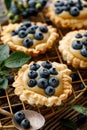 Small tarts made of puff pastry with addition fresh blueberries and caramel chocolate custard on a wooden rustic table, close up. Royalty Free Stock Photo