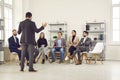 Small team of business people are listening to male speaker speaking in front of them in office. Royalty Free Stock Photo