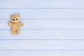 Small teddy bear on blue wooden background, top view