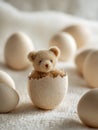 Small teddy bear emerging from a cracked eggshell surrounded by whole eggs on a soft textured surface with a warm, cozy atmosphere Royalty Free Stock Photo