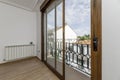 Small terrace with wrought iron railing, with wood-look aluminum access doors in a corner of a room with aluminum radiator