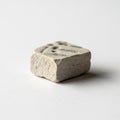 A small textured cube shaped stone sits on a plain white surface Royalty Free Stock Photo