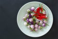 Small thai eggplants and red hot chili peppers on a green plates on a black background. Top view, asian food concept