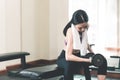 Small thin asian woman is lifting dumbbell in fitness club