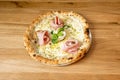 Small thin-crust baked pizza with goat cheese, mortadella mortadella slices, basil leaves, pistachio pieces Royalty Free Stock Photo