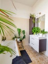 Small tiled bathroom with a bath and multiple green potted plants creating a tropical oasis