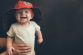 Small toddle standing near blackboard in a costume of a firefighter smiling. Happy and cheerful young boy.