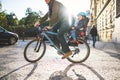 A small toddler boy sitting in bicycle seat with father outdoors in city.