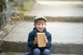 Small toddler is holding a large loaf of bread.