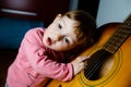 Small toddler listening to sound of a guitar
