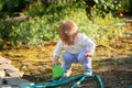 A small toddler is playing with a plastic toy bucket in the backyard. Summertime Royalty Free Stock Photo
