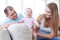 Small toddler standing while mom holding it and dad smiling