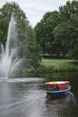 Small tourist boat passing a fountain in the city canals of Riga, Latvia Royalty Free Stock Photo