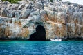 Small tourist motor boat with tourists on background of gorge. Entrance to a large cave in mountains of Mediterranean Royalty Free Stock Photo