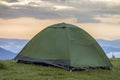 Small tourist tent on grassy mountain hill. Summer camping in mo Royalty Free Stock Photo