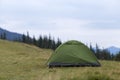 Small tourist tent on grassy mountain hill. Summer camping in mo Royalty Free Stock Photo