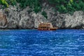 Small tourist wooden boat in blue water against the background of a rocky coast in Alanya Turkey. Beautiful seascape with a