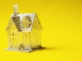 Small toy house with glitter on yellow color background. Copy space. Dreaming of glamourous high end fantasy home. Investment in