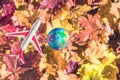 Small toy plane flying around globe Earth on the colorful autumn maple leaves background in the forest. Travel concept. Royalty Free Stock Photo