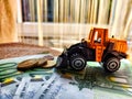 A small toy tractor or excavator on a bundle of money. The concept of the high cost of technology. The possibility of Royalty Free Stock Photo