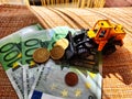 A small toy tractor or excavator on a bundle of money. The concept of the high cost of technology. The possibility of Royalty Free Stock Photo