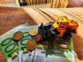 A small toy tractor or excavator on a bundle of money. The concept of the high cost of technology. The possibility of Royalty Free Stock Photo