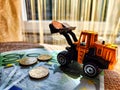 A small toy tractor or excavator on a bundle of money. The concept of the high cost of technology. The possibility of Royalty Free Stock Photo