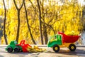 Small toy truck and tractor stands on a wooden surface against a background of a blurry autumn park Royalty Free Stock Photo