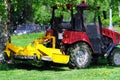 A small tractor mows the lawn. Landscaping of the area between the houses. City garden.