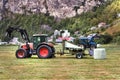 Small tractor with a round bale wrapper on a field in Geiranger, Norway