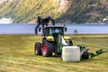 Small tractor with a round bale wrapper on a field in Geiranger, Norway