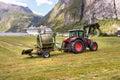 Small tractor with a round bale wrapper on a field in Geiranger, Norway