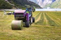 Small tractor with round baler unloading on a field in Geiranger, Norway