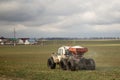 A small tractor runs in the field in early spring