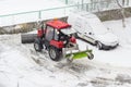 Small tractor snow plow in courtyard during work in snowfall