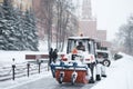 A small tractor sweeps snow from the sidewalk near the Kremlin walls