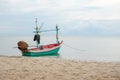 Small traditional fishing boat floating in the sea at coast with calm surface on ocean and clouded sky